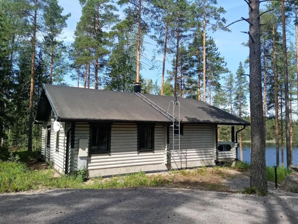 a small house in the woods next to a lake at Villa Norppa in Punkaharju