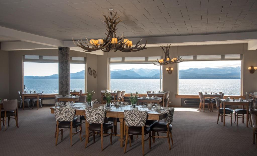 a dining room with tables and chairs and a view of the water at Hotel Tres Reyes in San Carlos de Bariloche