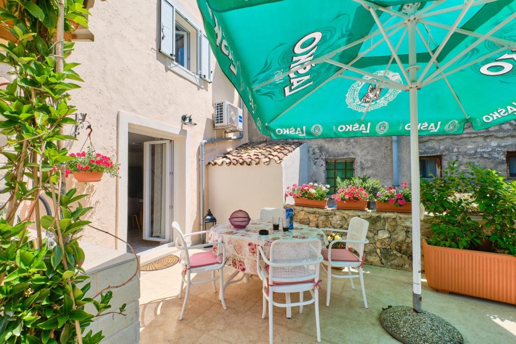 een patio met een tafel en stoelen en een parasol bij Apartment Kaleta in Sveti Jakov