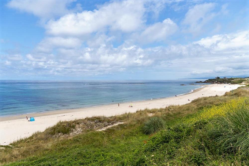 a beach with people on the sand and the water at Apartagal-Playa de Llas, Foz in Foz