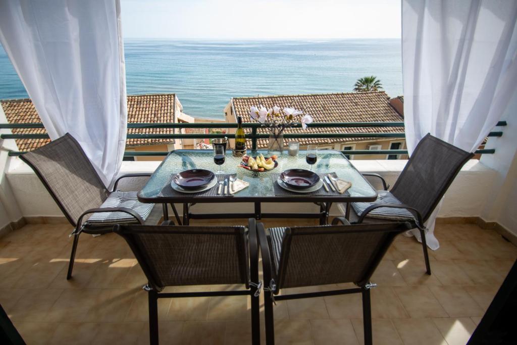 a dining table and chairs with a view of the ocean at Alexandras On The Beach and Pool apt in Glyfada