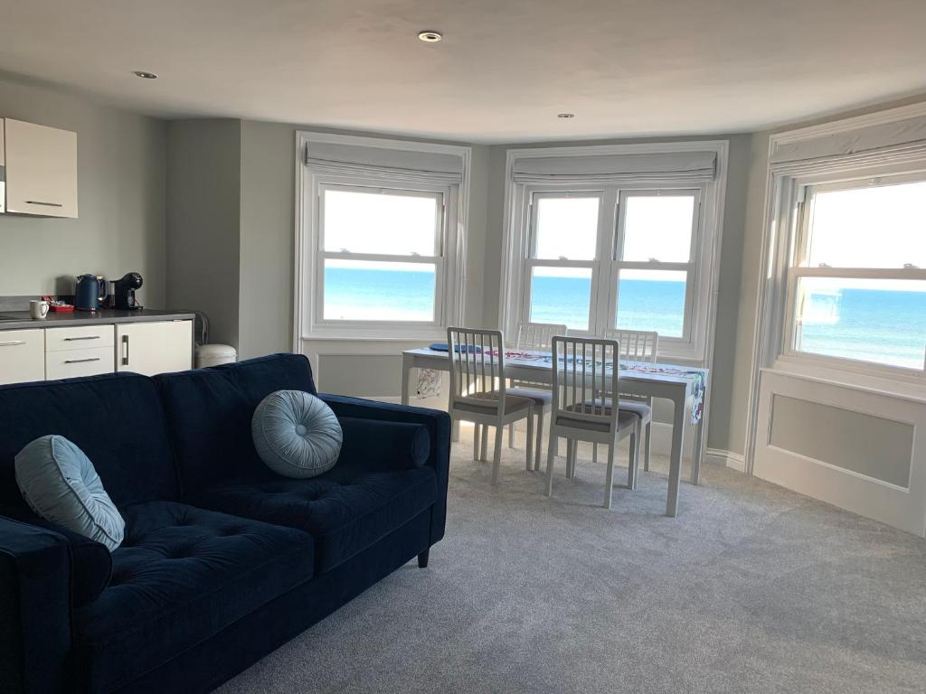 a living room with a couch and a table and chairs at Stunning Beachfront Apartment, Perfect Sea View. in Worthing