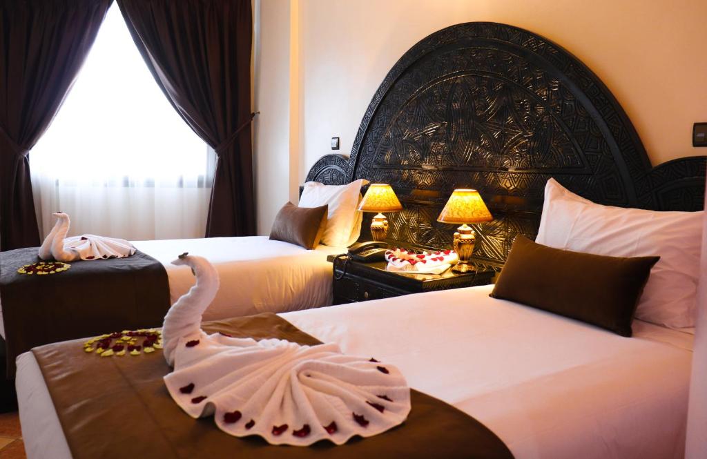 een hotelkamer met 2 bedden en een zwaan op een tafel bij Hôtel Riad Salam Agadir in Agadir