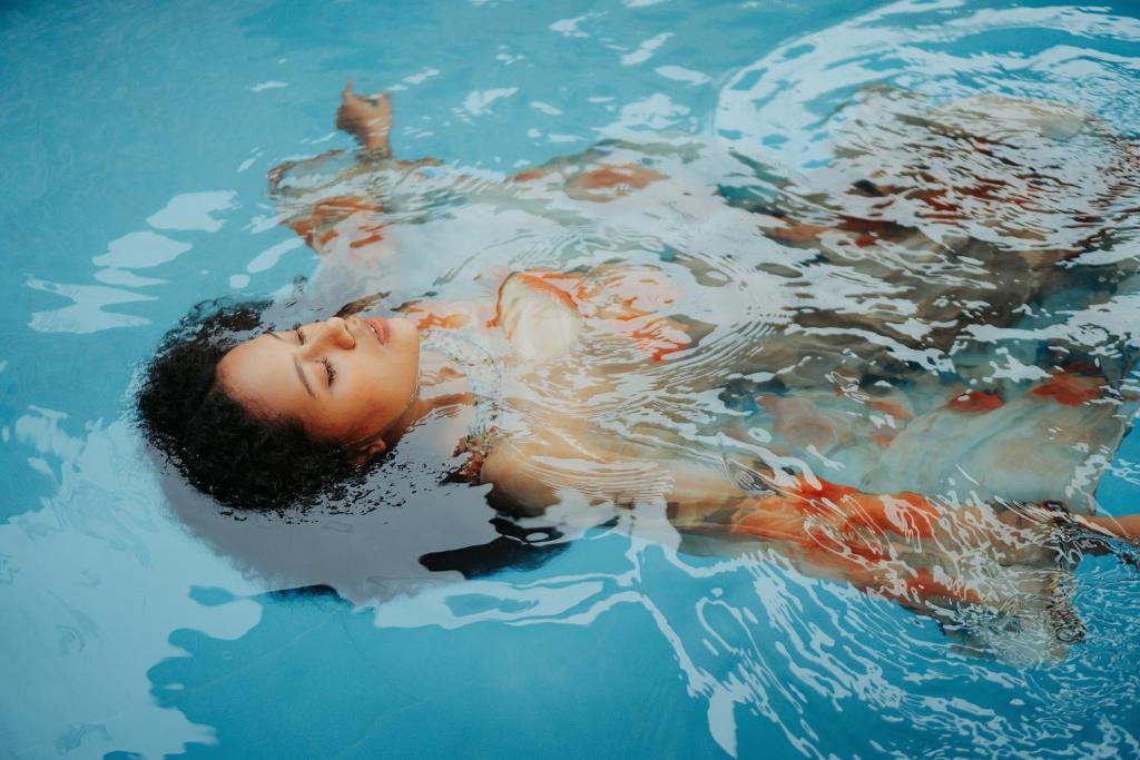 a boy laying in the water in a swimming pool at The Segond Hotel in Xagħra