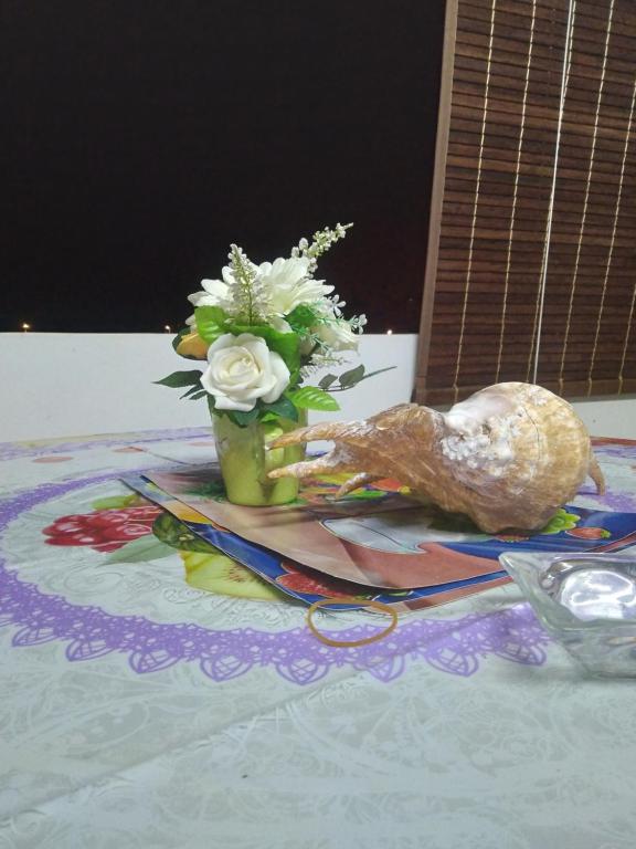 Un jarrón de flores y un pollo sobre una mesa. en Chez Bablou, en Grand Baie