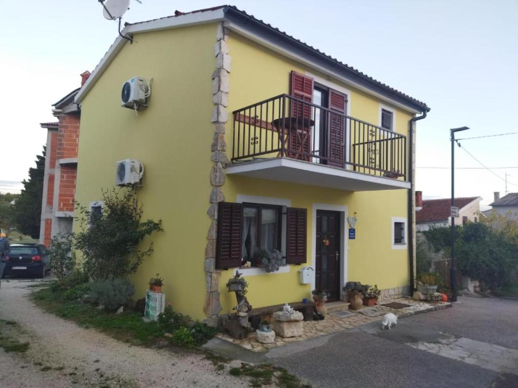 a yellow house with a balcony on a street at Apartment Josipa 1 in Premantura