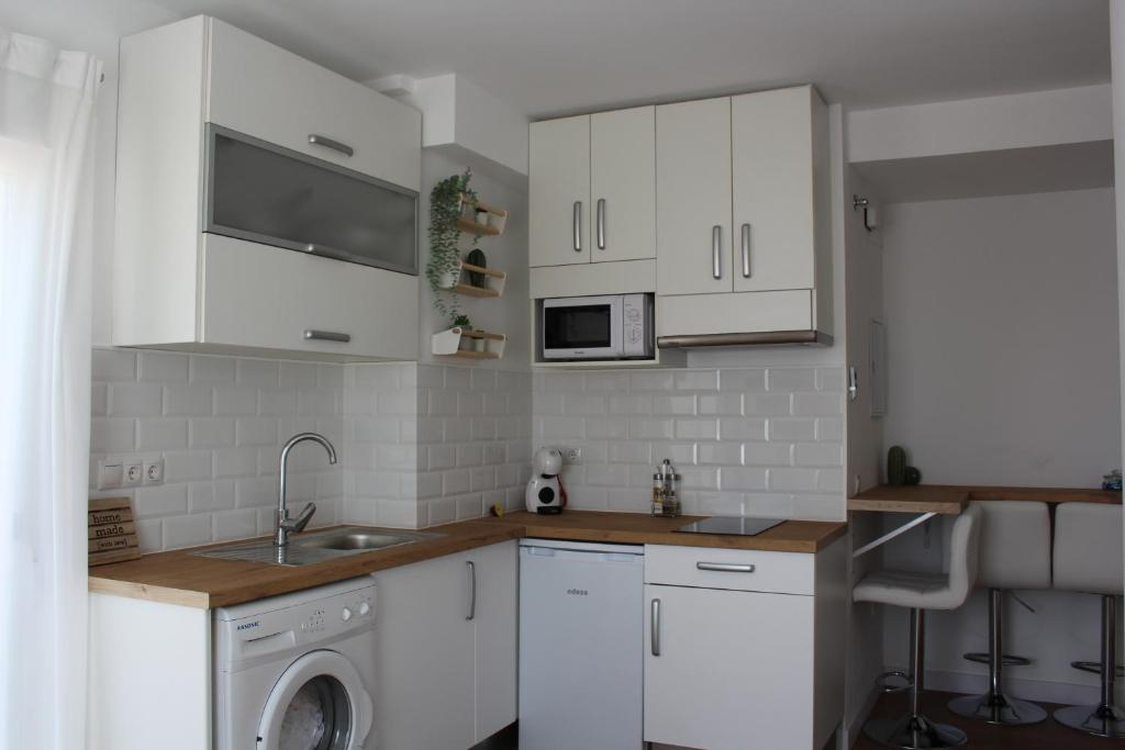 kuchnia z białymi szafkami i pralką w obiekcie Beautiful brand new 2 bedroom flat with terrace w Maladze