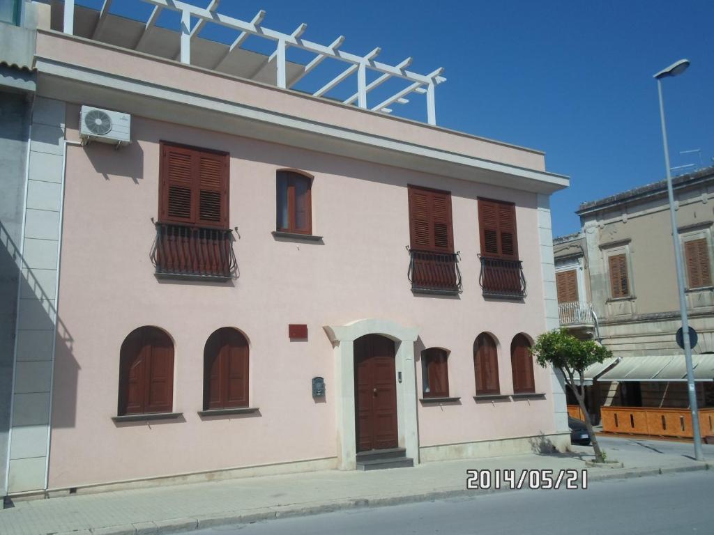biały budynek z brązowymi drzwiami i oknami w obiekcie B&B Home Sweet Home Rosolini w mieście Rosolini