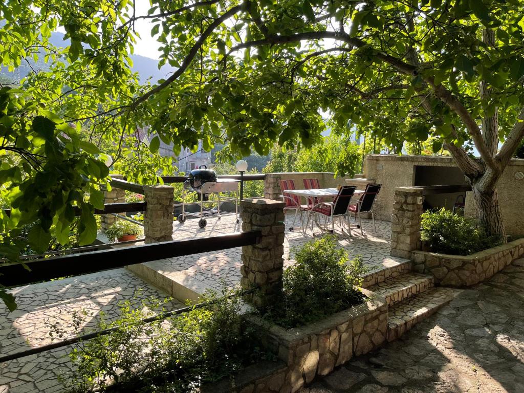 een patio met een tafel en stoelen onder een boom bij Apartments Šmit in Cres