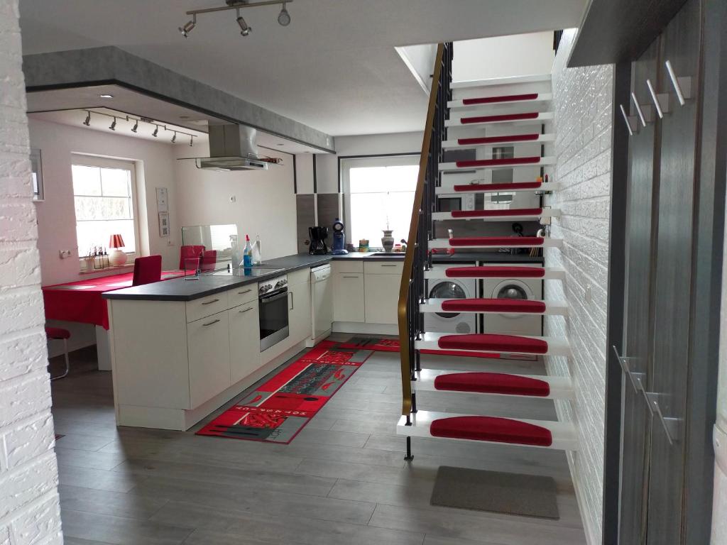 a kitchen with a spiral staircase with red accents at Exklusive FeWo Papenburg mit Terrasse & beheiztem Wintergarten in Papenburg