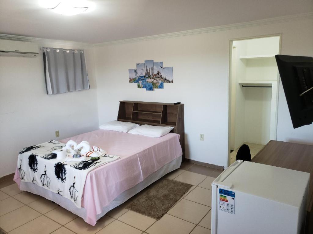 um quarto com uma cama grande e um cobertor rosa em Enseada Suítes em Guarapari