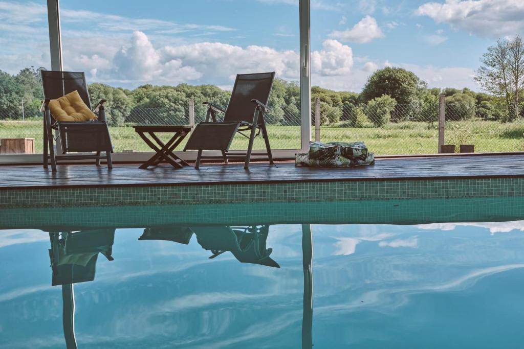 twee stoelen en een tafel naast een zwembad bij Casa Jacoba Pool House by Serendipia Turismo in Ortoño