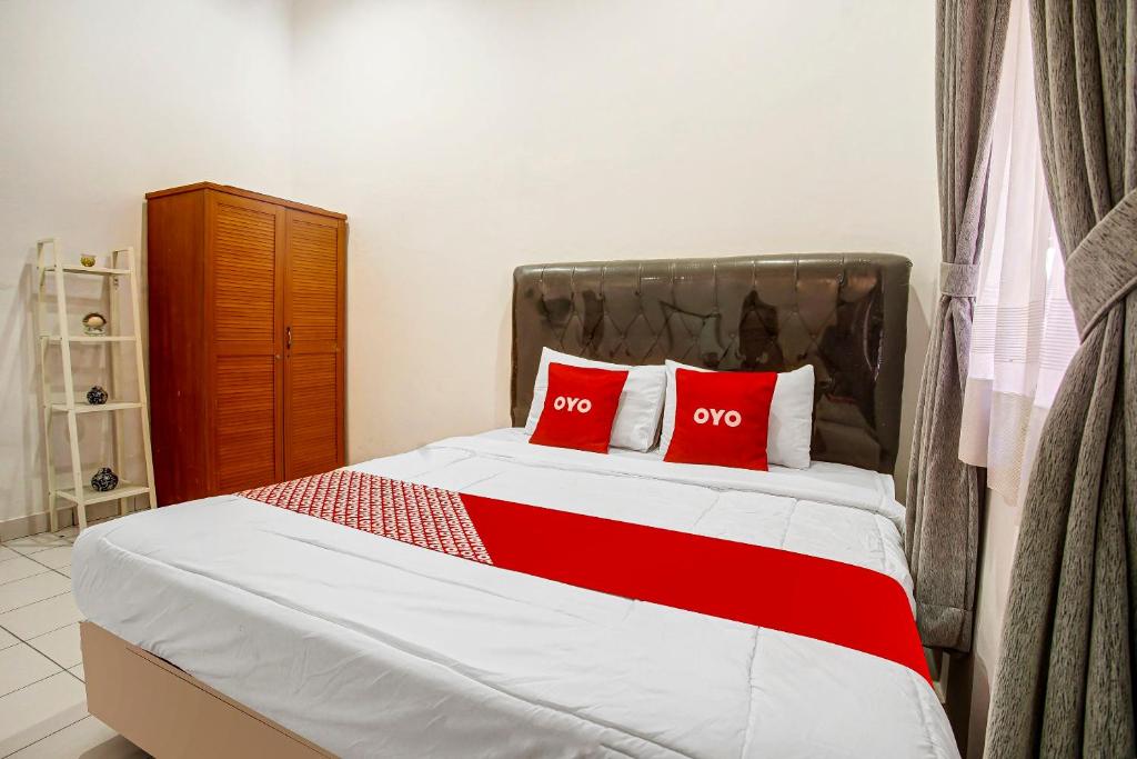 1 dormitorio con 1 cama con 2 almohadas rojas en OYO 91055 Homestay Syariah en Bandar Lampung