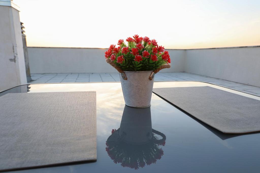 un jarrón con flores rojas en una mesa en serendipity la terrazza house en Lecce