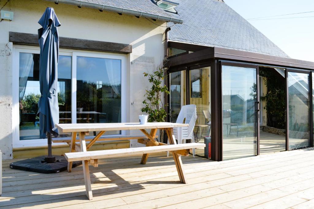 une table de pique-nique et un parasol sur une terrasse dans l'établissement La maison penchée, avec jardin à 50m de la plage, à Asnelles