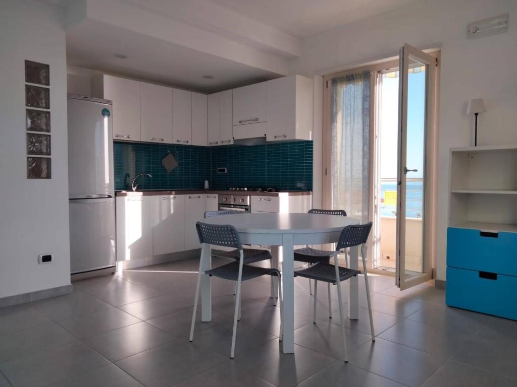 een keuken met een tafel en stoelen en een koelkast bij CASA BELLAVISTA in Nicotera