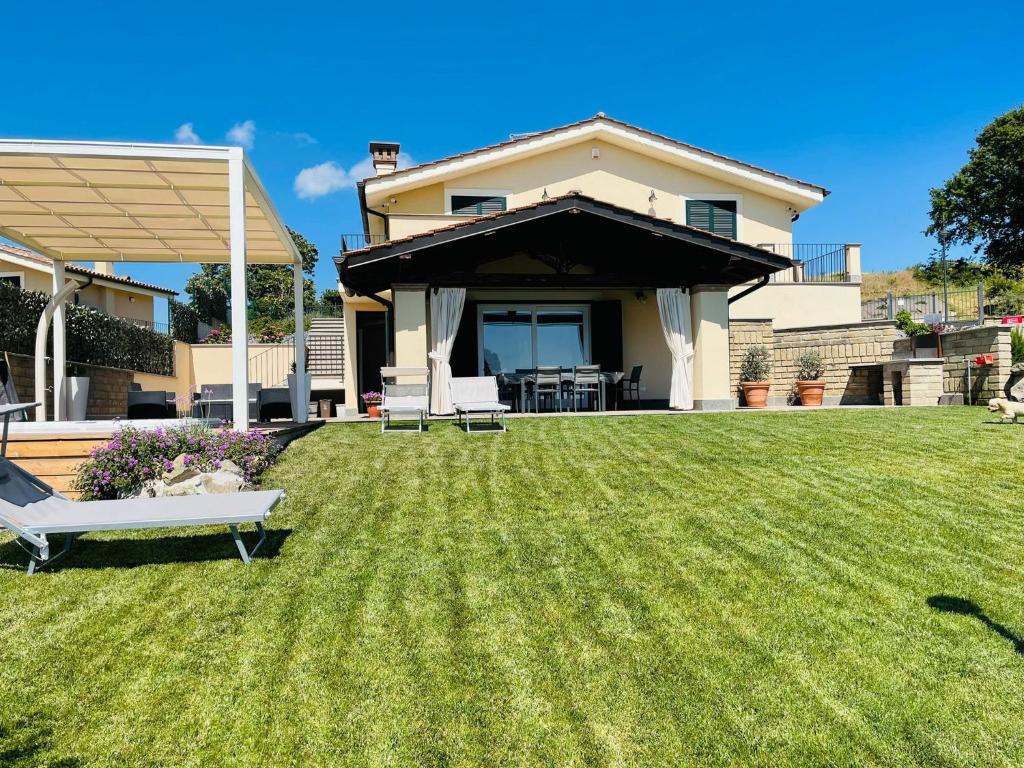 ein Haus mit einem Garten mit grünem Gras und einem Haus in der Unterkunft Casa Vacanze Lago Blu in Trevignano Romano