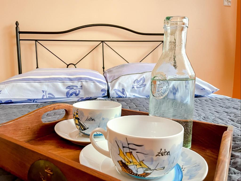 un vassoio con due tazze e una bottiglia sul letto di Fiord a Łeba