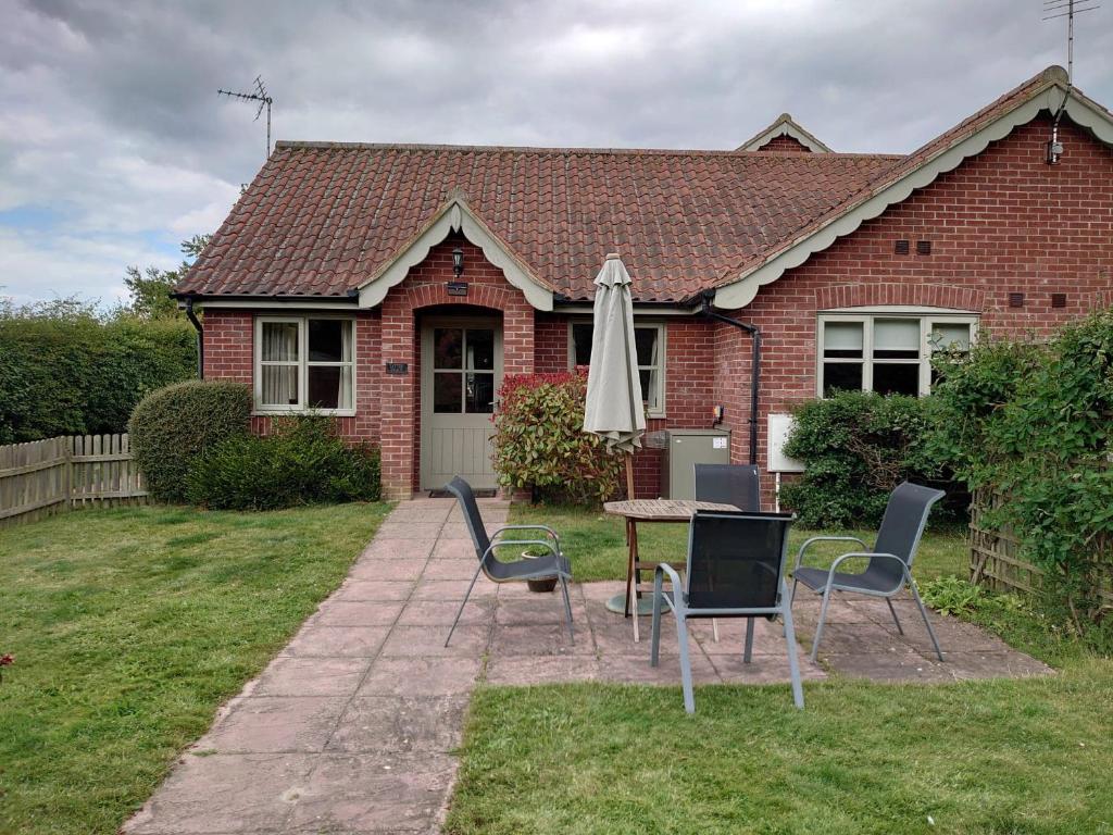 a table and chairs with an umbrella in front of a house at Little Broad Cottage Norfolk 2 Bedroom Sleep 4 in Great Yarmouth