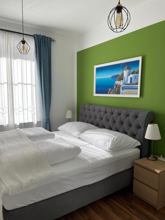 a bedroom with a large white bed with green walls at Studios Klagenfurt in Klagenfurt