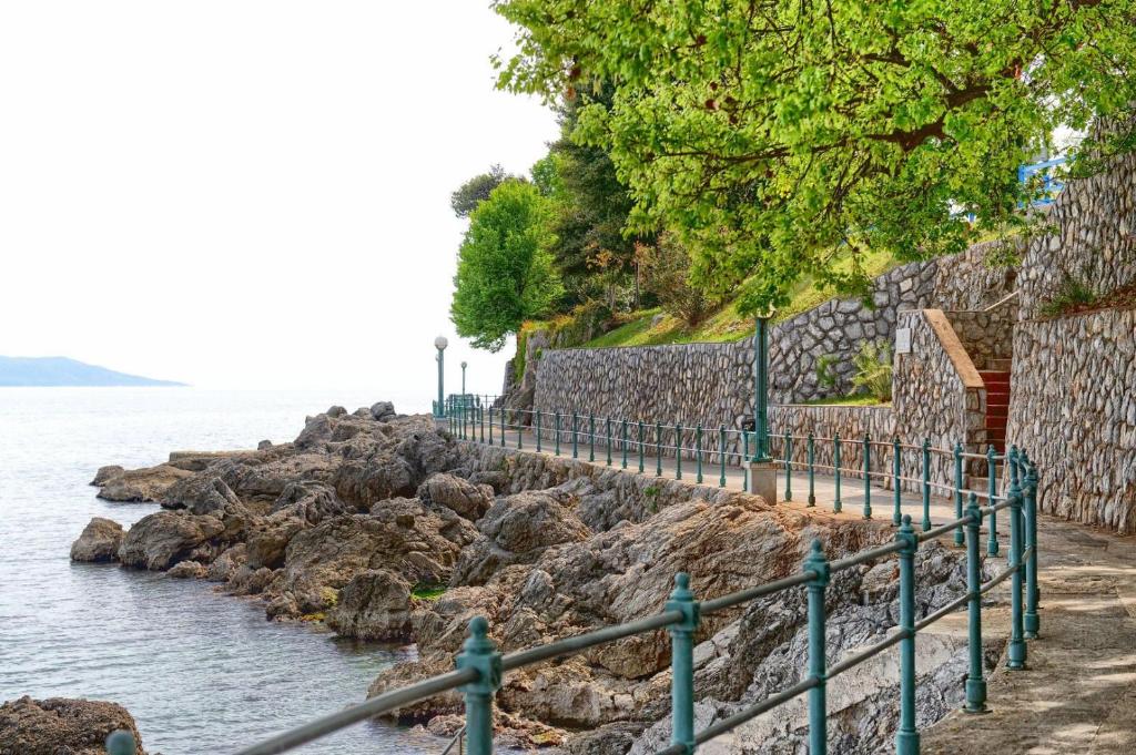 a path next to the water with a stone wall at Villa Beller New in Ičići