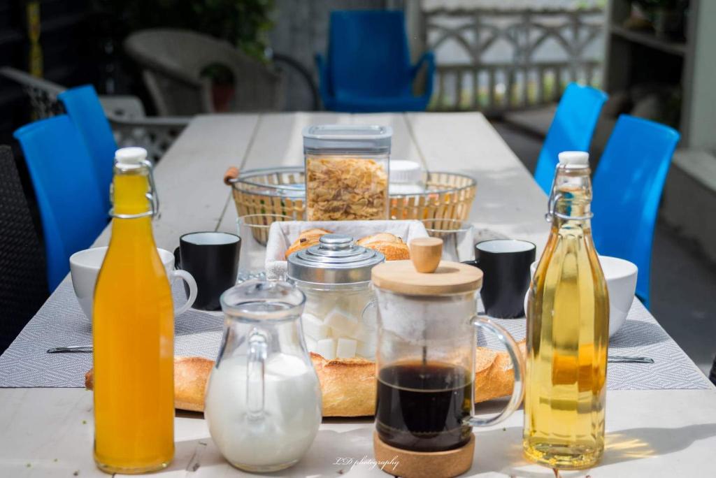 una mesa con botellas de zumo y pan. en HOULALA Gîte & Chambres d'hôtes, en Pont-Évêque