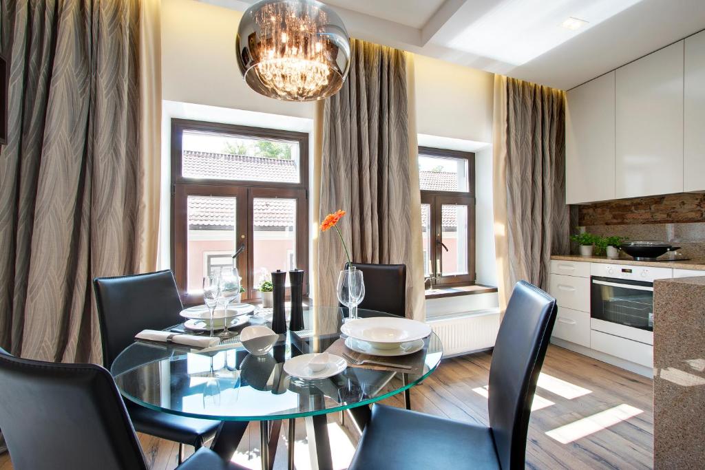 een eetkamer met een glazen tafel en stoelen bij Angel Wing Apartamentai in Vilnius