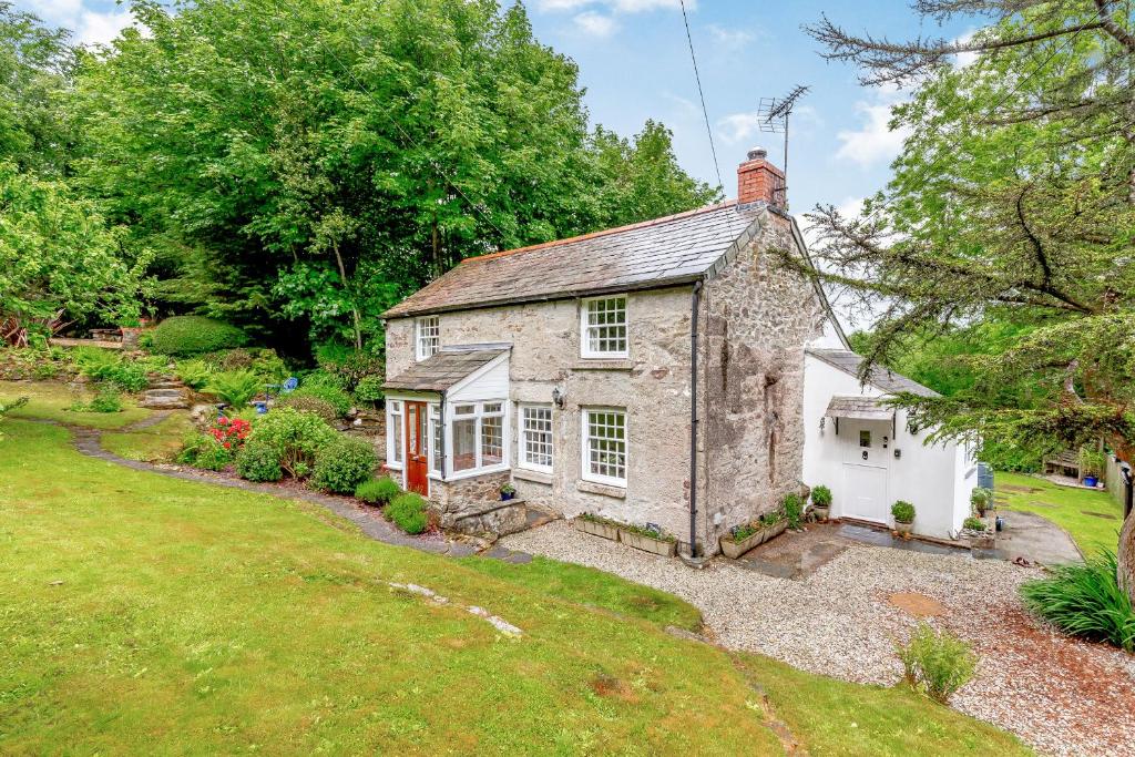 ein altes Steinhaus in einem Garten mit Hof in der Unterkunft Westside Cottage in Bodmin