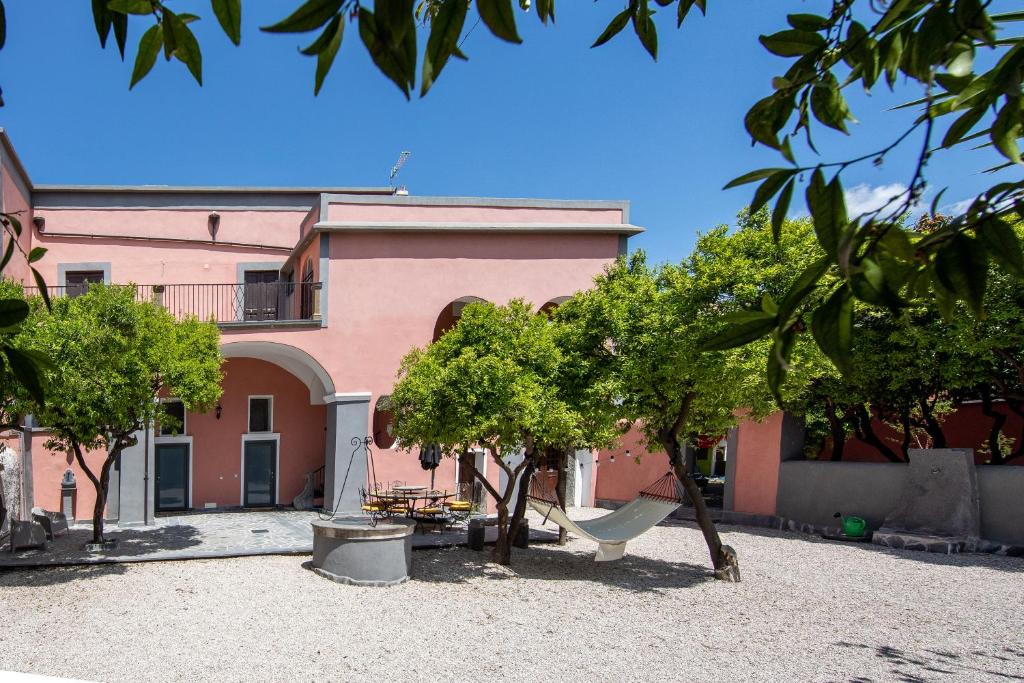 a pink house with trees in front of it at Palazzo d'Aquino in Boscoreale