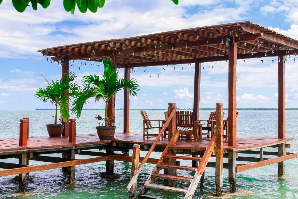 a wooden pier with chairs and a pavilion on the water at Villa Marcela in Calderitas