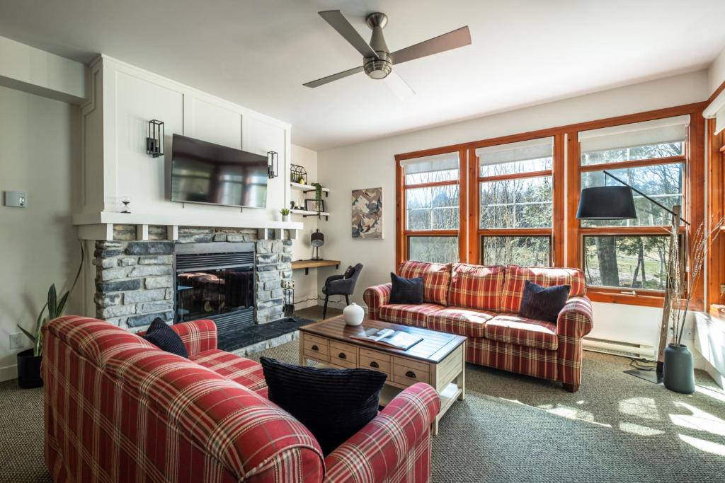 a living room with two couches and a fireplace at Le Serein Condo 1 chambre à Tremblant Les-Eaux in Mont-Tremblant