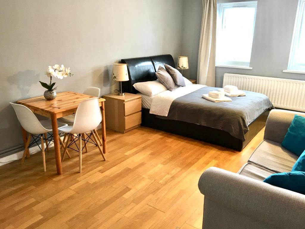 a bedroom with a bed and a table and a couch at Lovely Studio Room in the heart of Kingston upon Thames in Kingston upon Thames