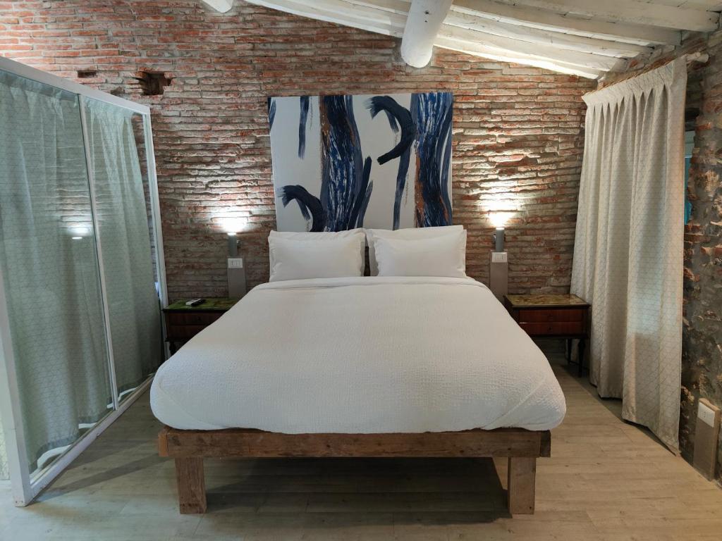 a bedroom with a large bed with white sheets at Inside the Wall in Lucca