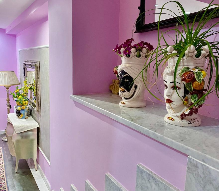 two vases on a shelf in a room with purple walls at Hotel Scilla in Scilla