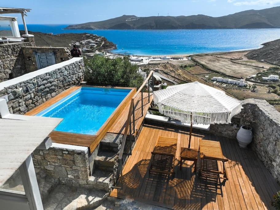 a swimming pool with chairs and a view of the ocean at Amelia Private Pool Apartment in Panormos Mykonos