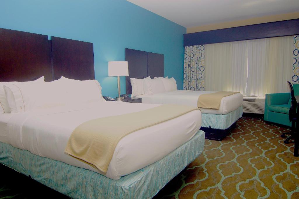 two beds in a hotel room with blue walls at Holiday Inn Express Hotels & Suites Cuero by IHG in Cuero