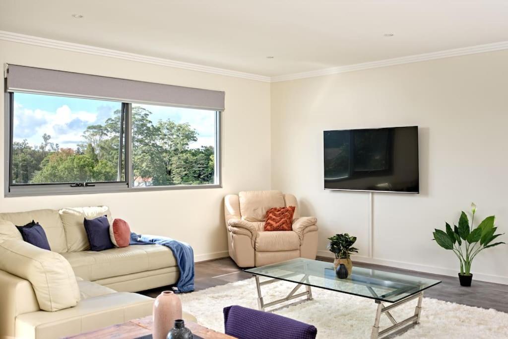 sala de estar con sofá y TV en Large Premium Warrawee Apartment with Parking A401 en Warrawee