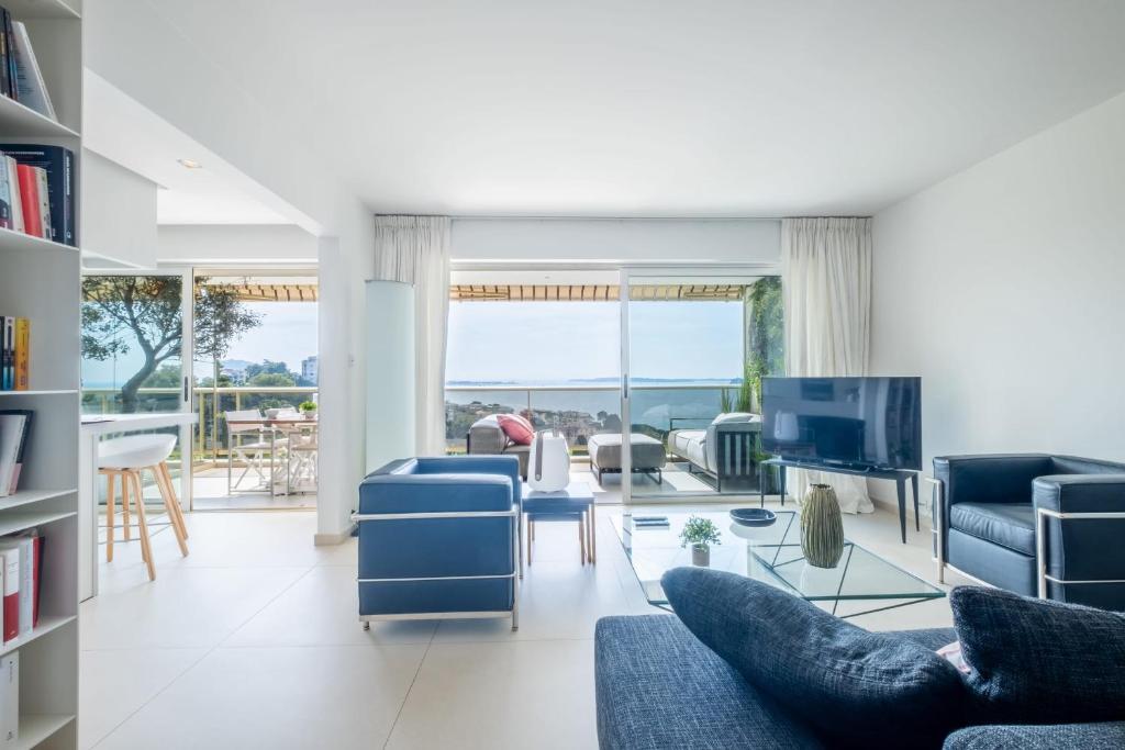 un salon avec des chaises bleues et une télévision dans l'établissement  SERRENDY  3 pièces sur les hauteurs de Cannes dans domaine de standing !, à Cannes