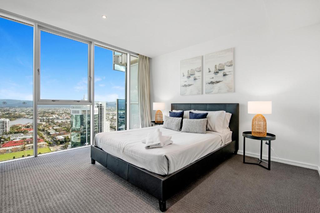 una camera con un grande letto e ampie finestre di H'Residences - 2 & 3 Bedroom Ocean View in the heart of Surfers Paradise! a Gold Coast
