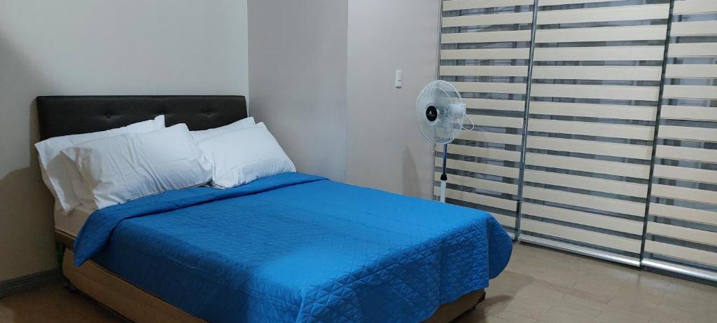 81 Newport,NAIA 3,Pasay Condotel في مانيلا: غرفة نوم بسرير ازرق ومروحة