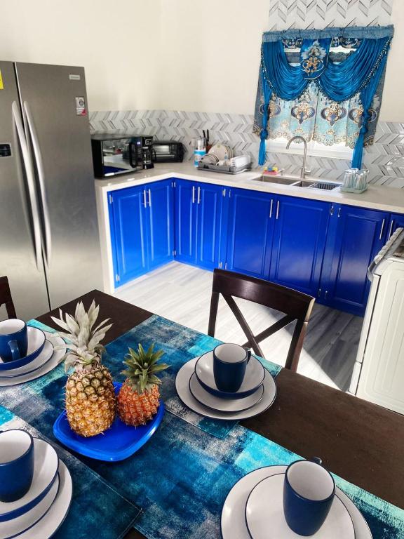 a kitchen with blue cabinets and a table with hats and pineapple at Carnbee Cozy Cottage in Bethel