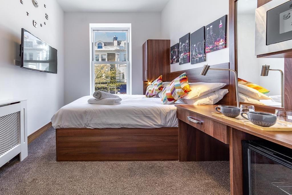 a bedroom with a bed and a desk and a window at 205 Earls Court Rooms in London