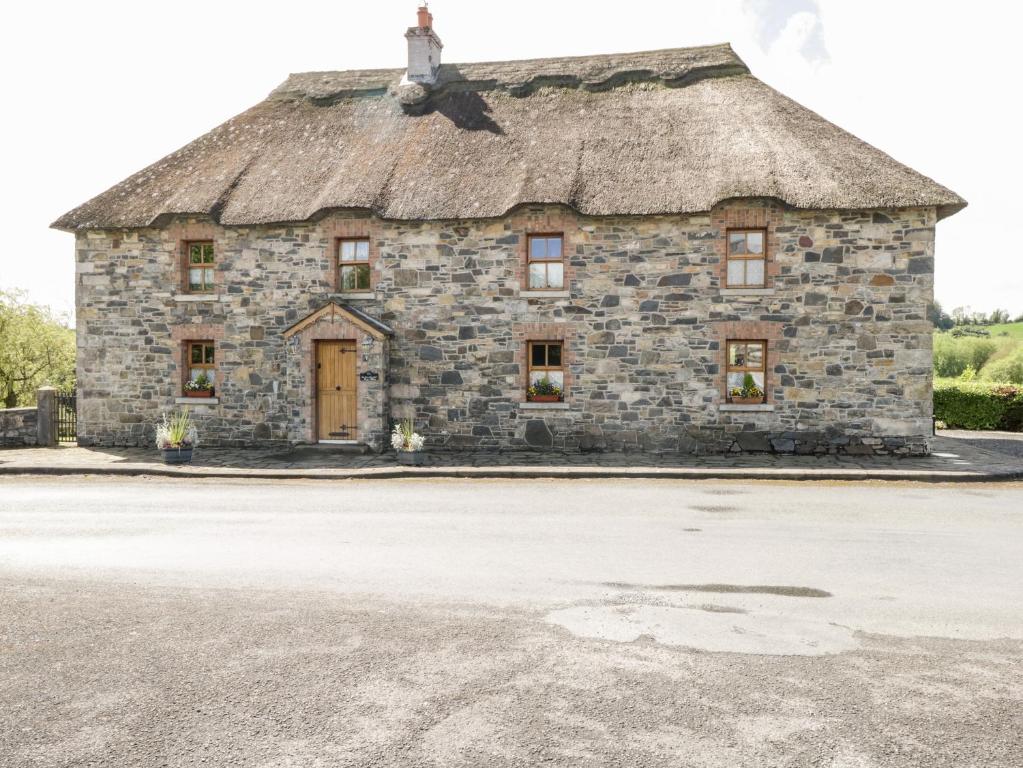 un antiguo edificio de piedra con techo de paja en An Maide Bán, en Cootehill