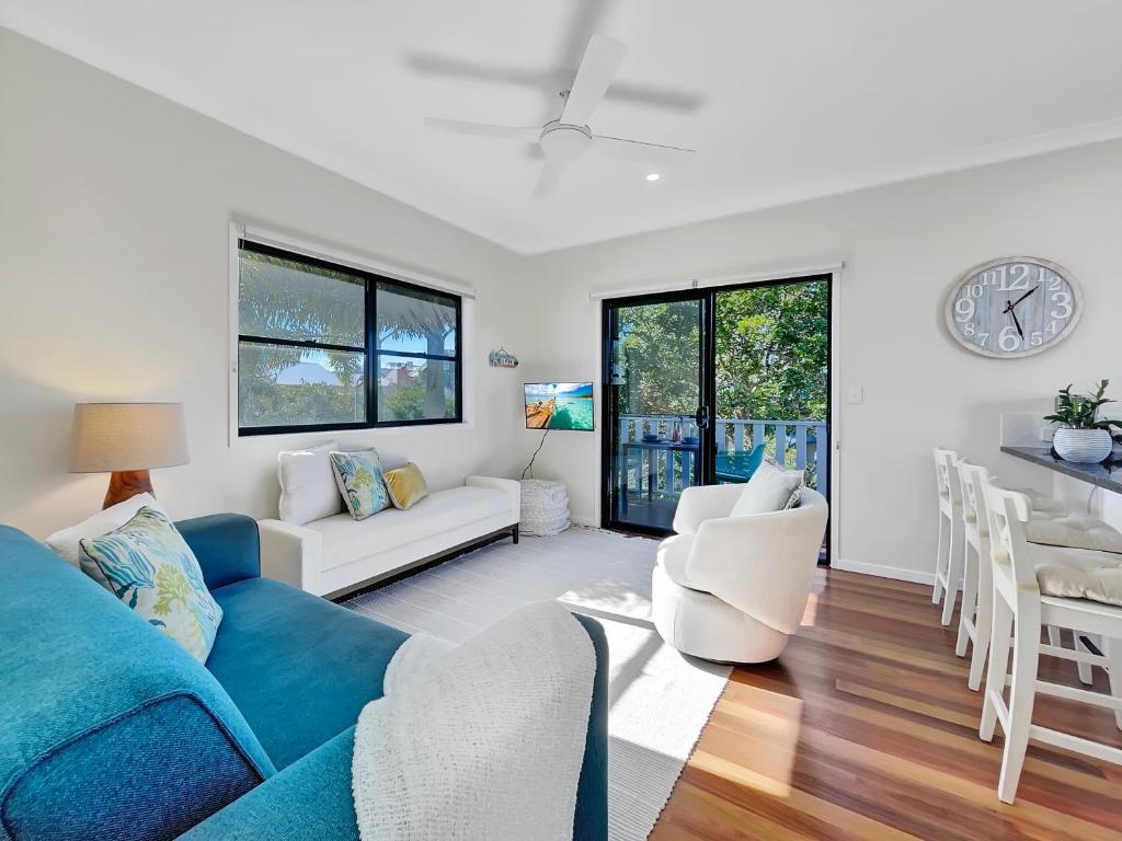a living room with a blue couch and a table at Serene Beachside Apartment in Marcoola