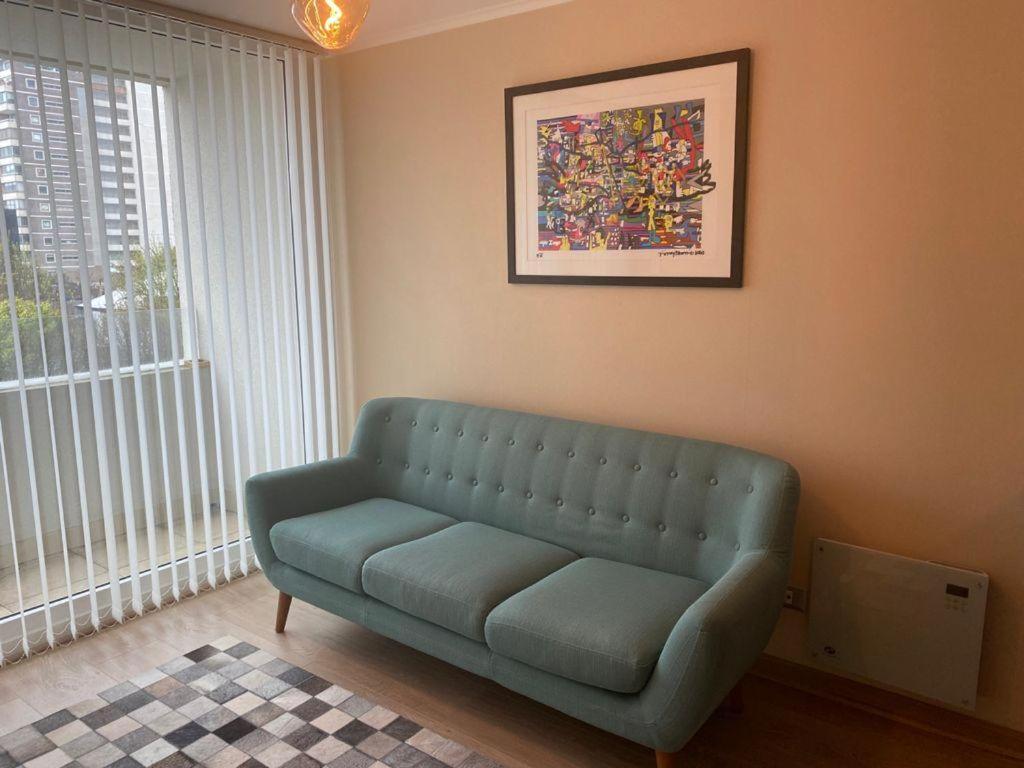 uma sala de estar com um sofá azul em frente a uma janela em Departamento Centro Chillan em Chillán
