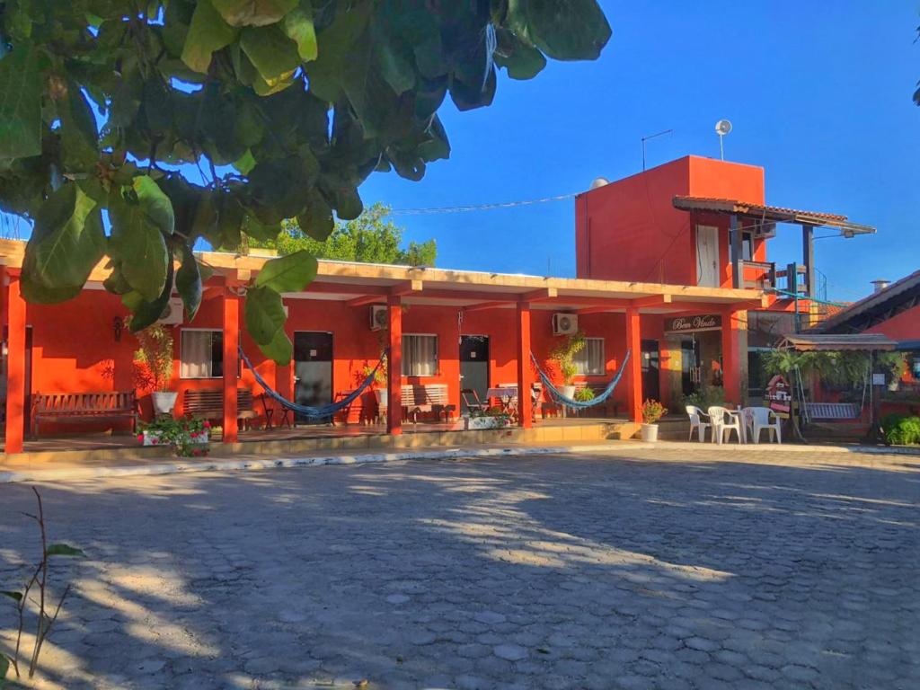 un bâtiment rouge avec des tables et des chaises devant lui dans l'établissement Pousada caminho da fé, à Aparecida