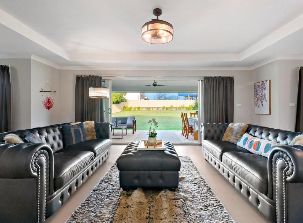 a living room with leather couches and a table at Wine Down Manor in Cessnock