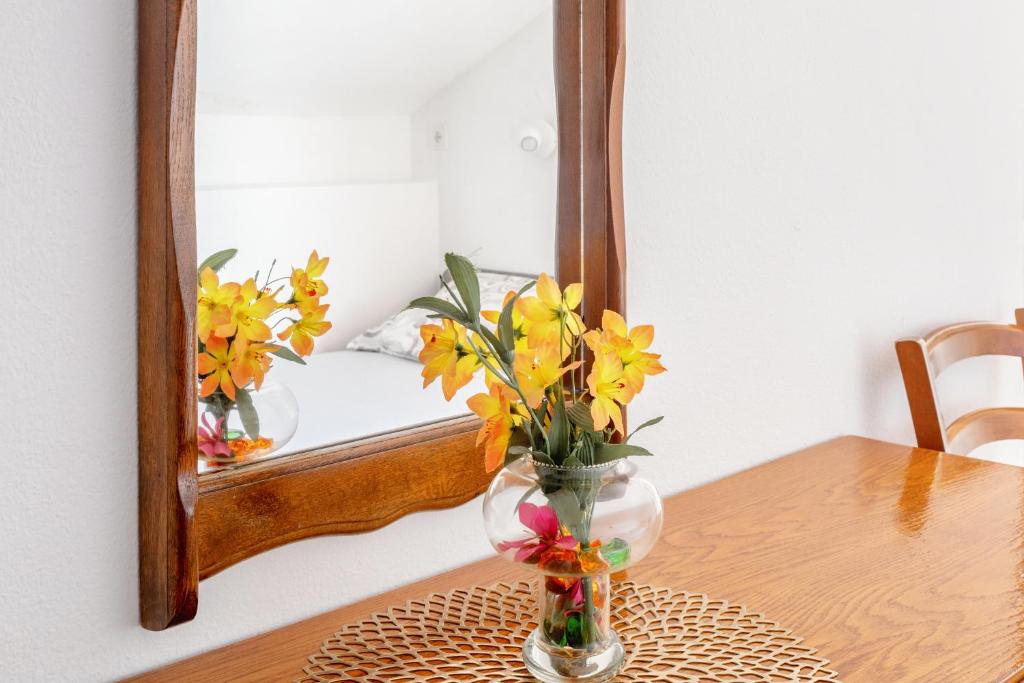 a vase with flowers on a table in front of a mirror at Villa M&M - ZF Hvar in Hvar