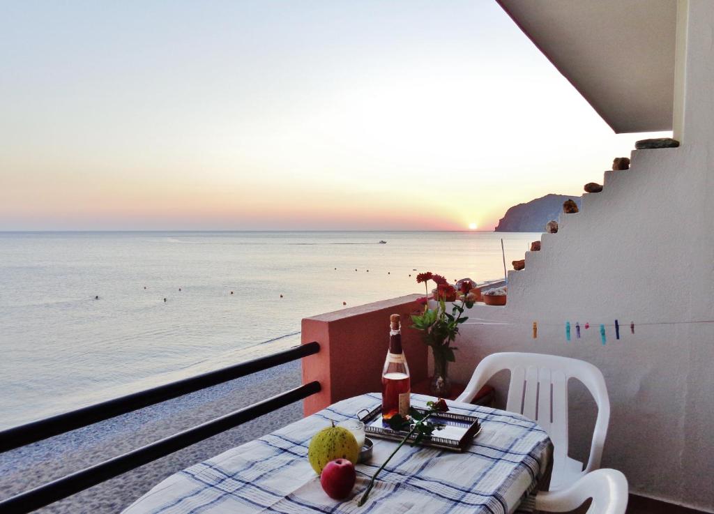 a table with a bottle of wine on a balcony overlooking the ocean at Marilena in Skala Eresou