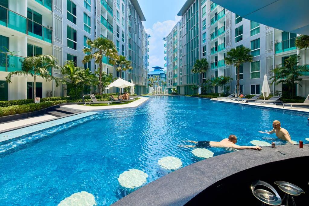 two people laying in a swimming pool in a building at City Center Residence by Tech in Pattaya Central